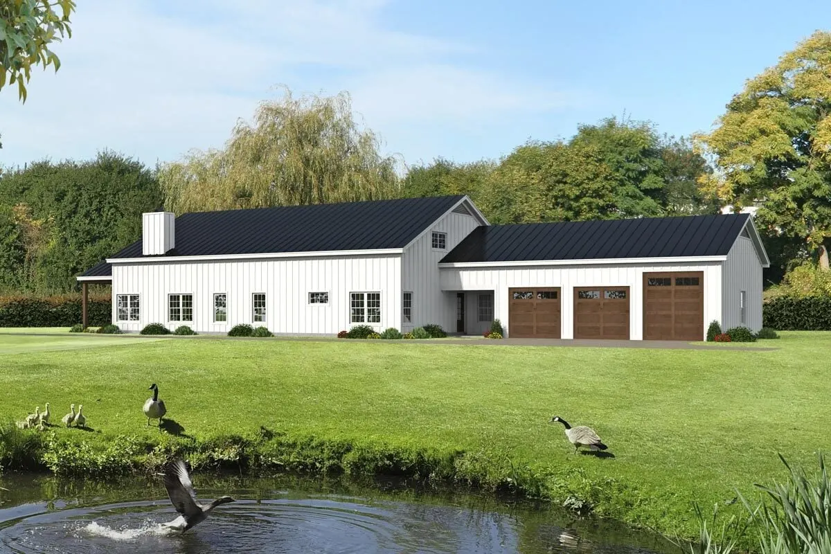 A wide view of the barndominium with an attached vaulted garage that has three side entry doors. 