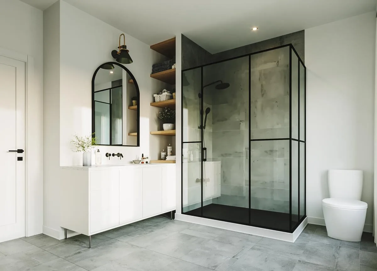 A clear glass shower in a black frame with a white side vanity and toilet.