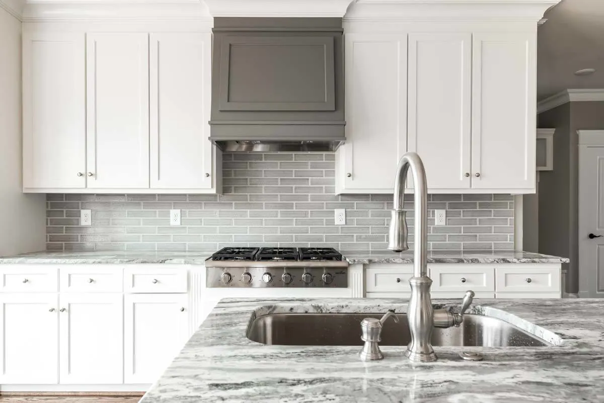 The modern kitchen interior is completed by the gray brick backsplash.