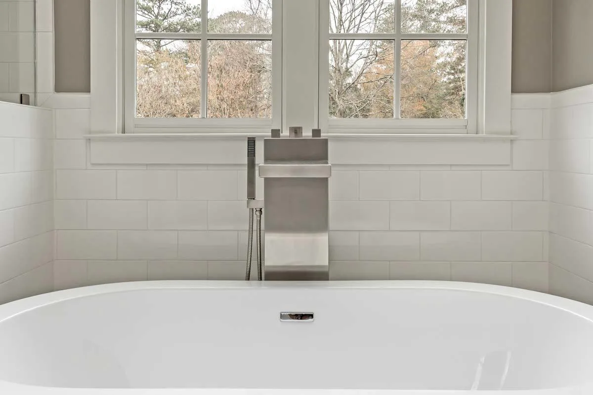 Bathtub area near to window with a view of the outdoors.
