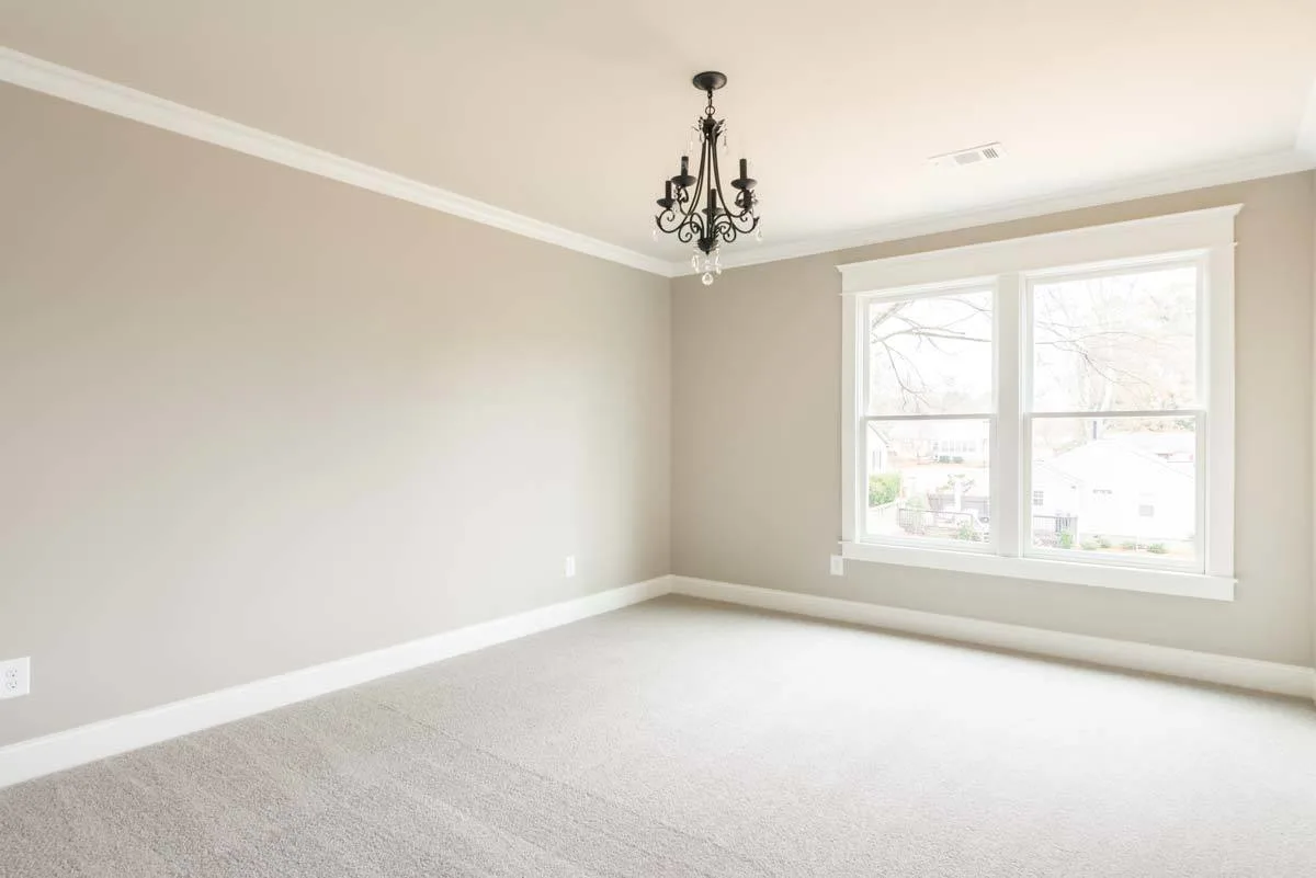 A spacious bedroom with beige carpeting that matches the wall hue.