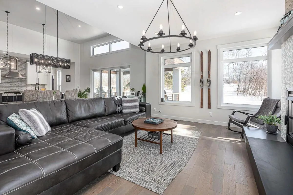 The black leather sofa and chandelier go well together in the living space.