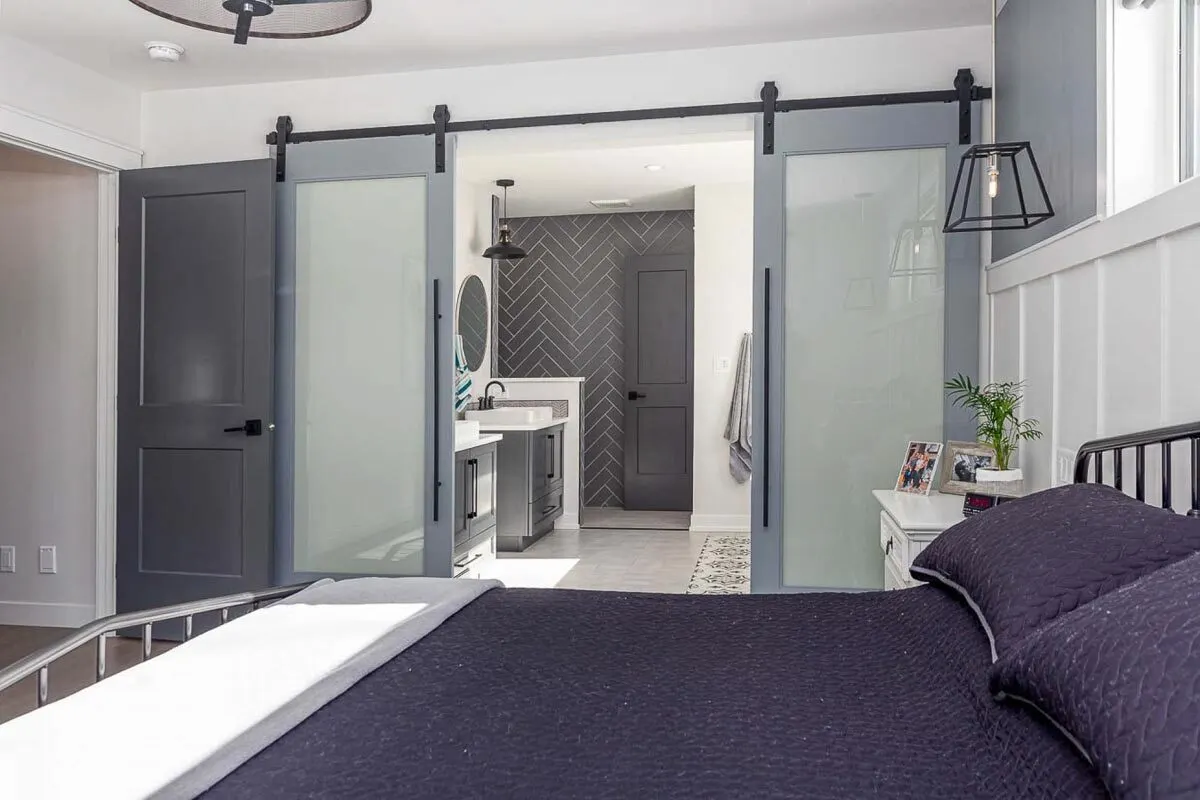 A glass sliding barn door of the bathroom in a gray color frame.
