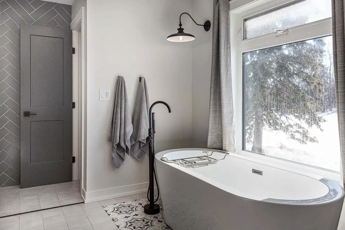 The bathtub area is next to the glass window with a view of the outdoor.