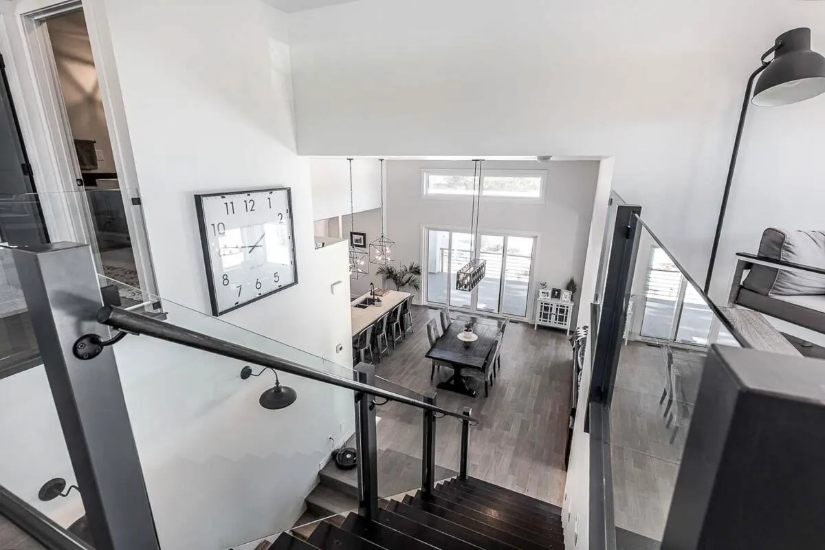 Stairs with black paint with a glass panel in the railing, as seen from the upper-level area.