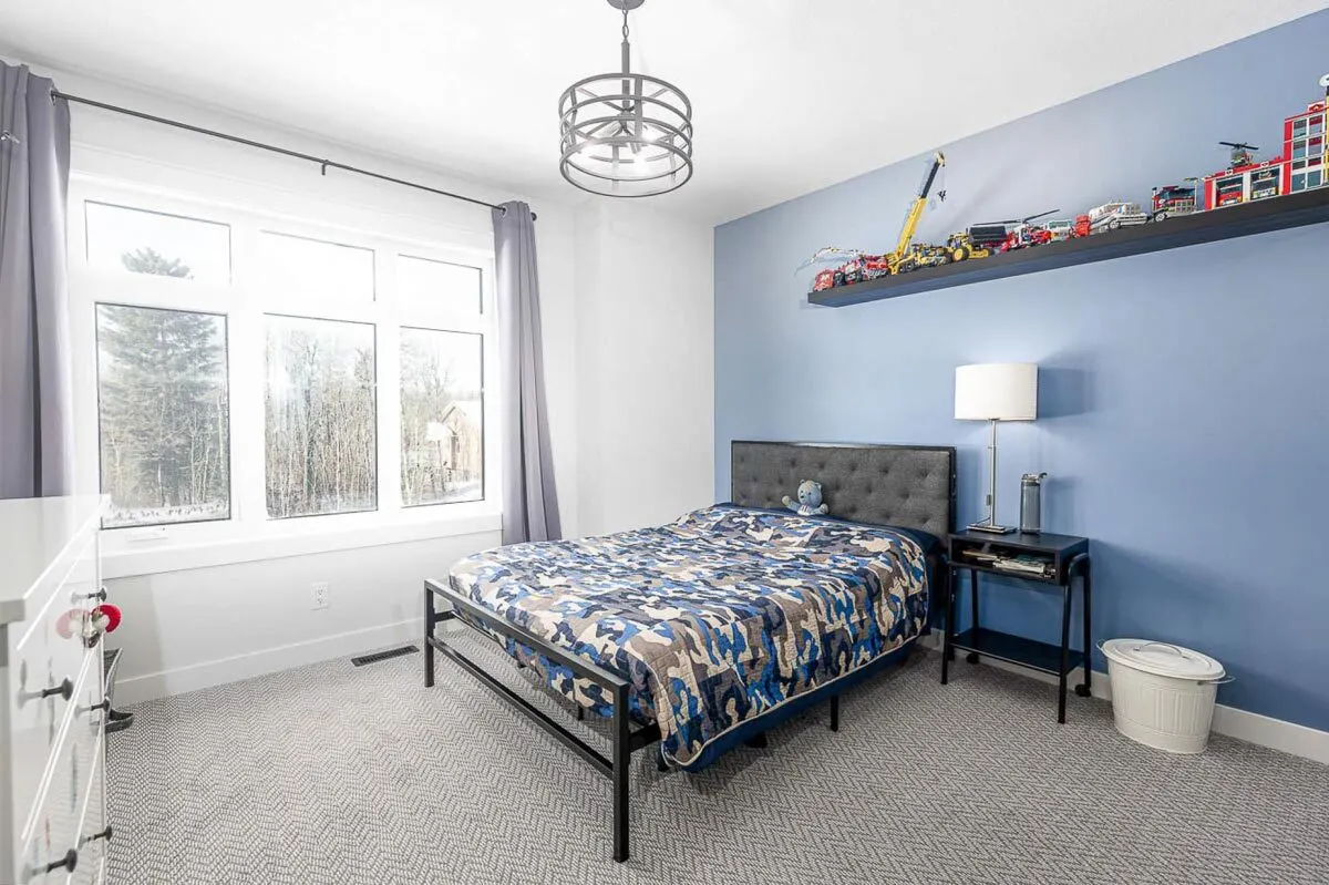 A kid's modern bedroom with blue walls and toy decorations over the bed.