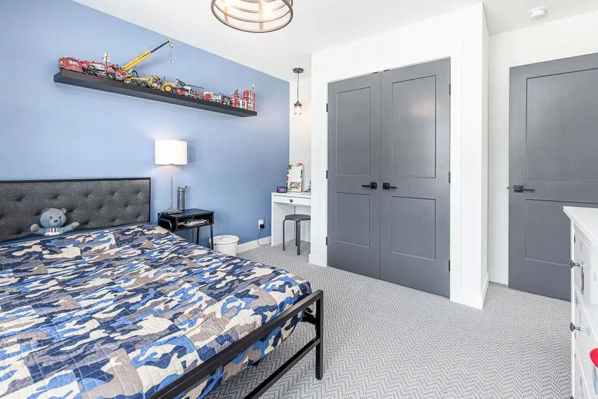 There is a study desk next to the big gray door in the bed's side corner.
