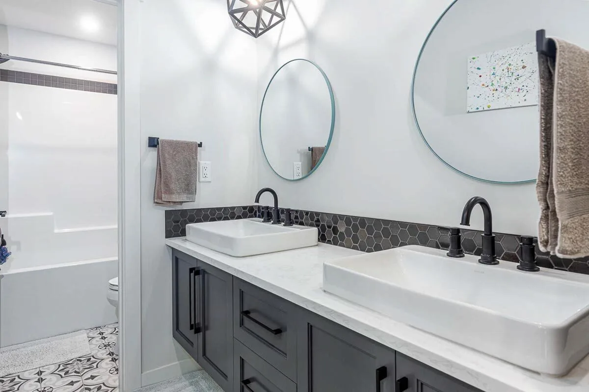 Vanities with a white sink, a circular mirror on the wall, and a countertop blend well together.