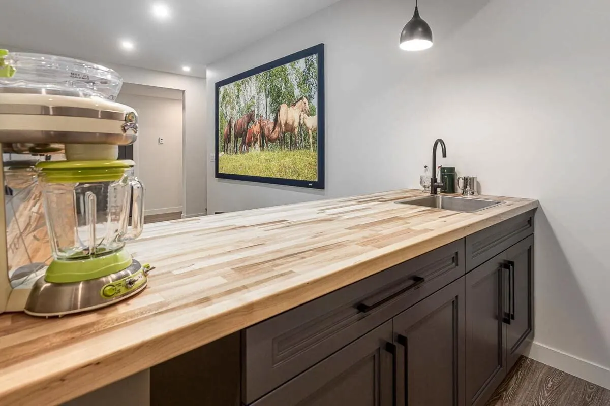 An area with a wet bar and a long service table with a sink.