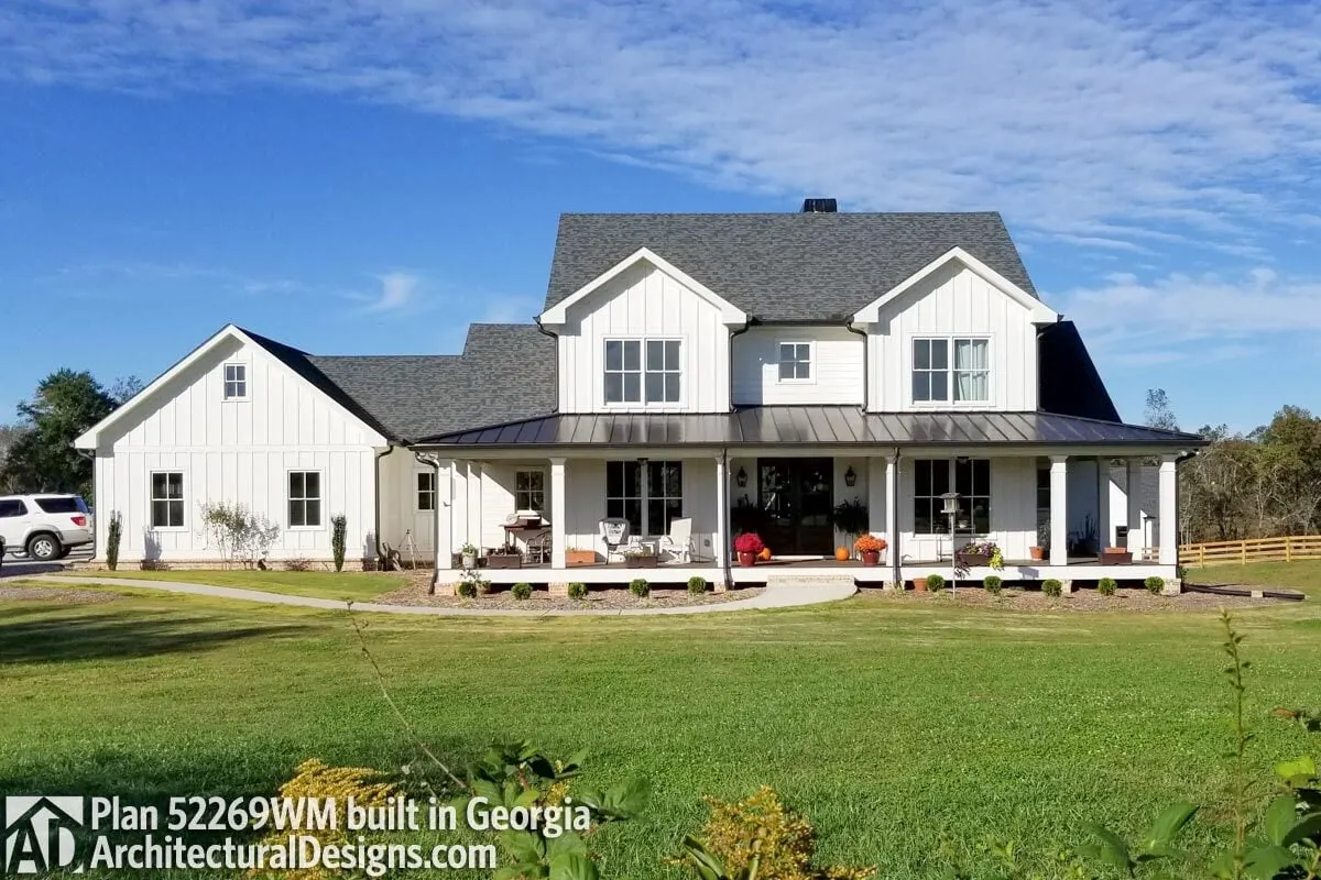 A view of the farmhouse that centers on a wraparound porch and a French door.
