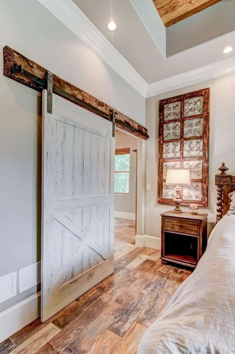 A barn-style door in white paint creates an eye-catching appearance in the bedroom.