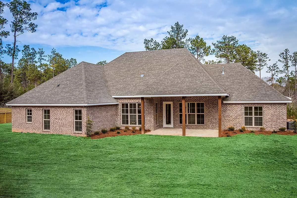 Craftsman house with brick-style walls in a large green yard.