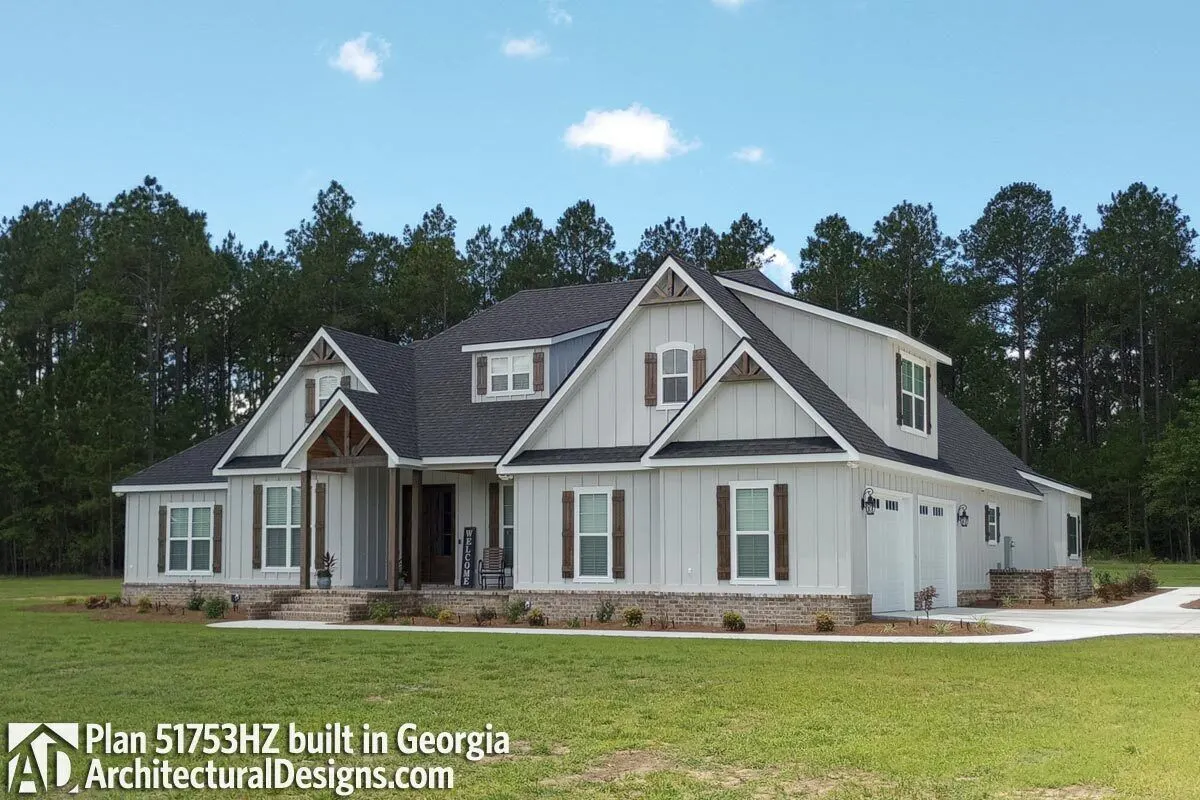 The house's white and gray façade combines wonderfully with the wooden accent shutters and door in a barn-style design.