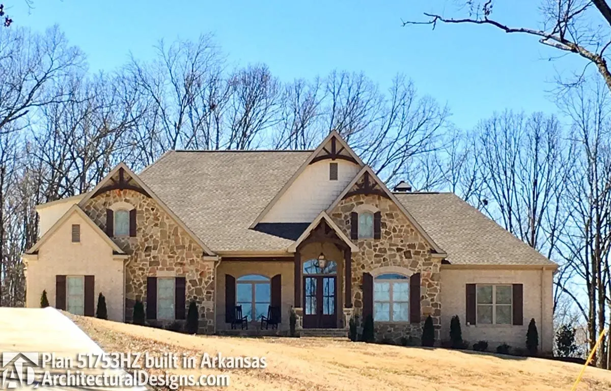A sophisticated craftsman home architectural design with large portions of stone as the wall design.