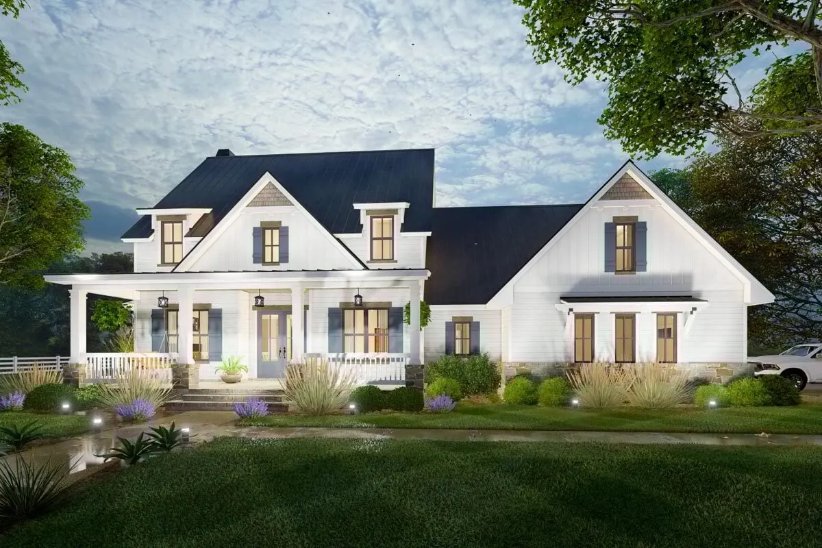 The lights on the ground provide for a wonderful nighttime view of a modern farmhouse.