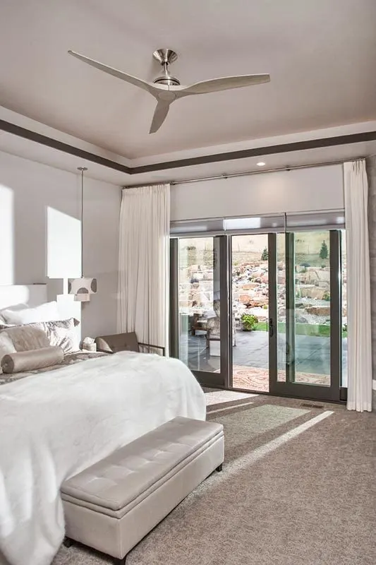 The master bedroom is decorated in white and has access to a covered patio.