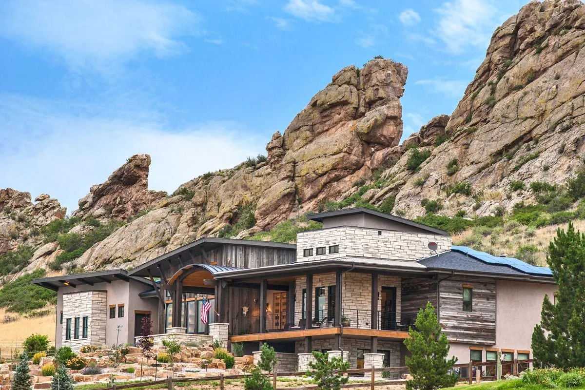 The outside of the home with wood and stone looks great with black wood supports.