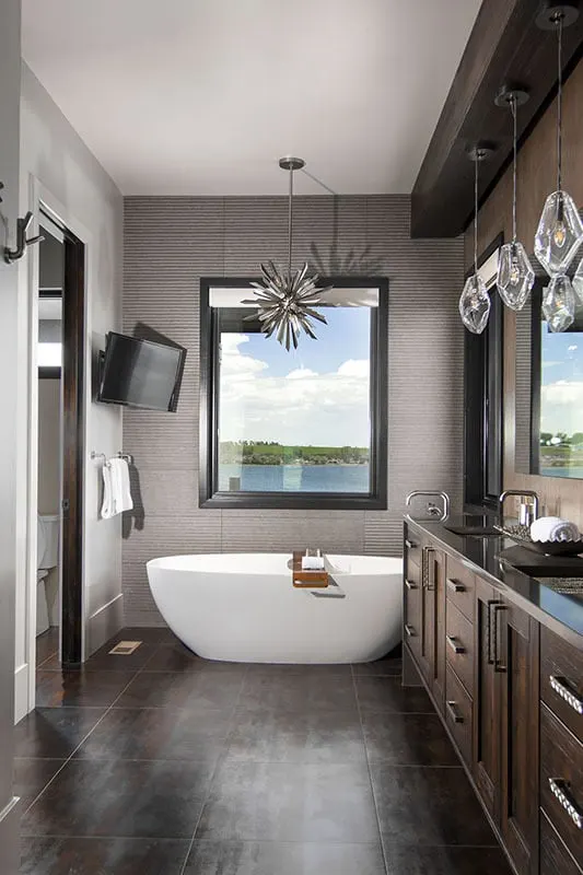 The bathroom features a vanity with a dark wood accent design, a tub, and an additional television for entertainment.