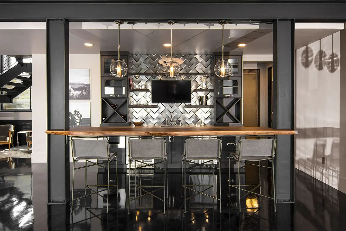 A stylish bar area with a prominent wooden table and a black elegant exterior.
