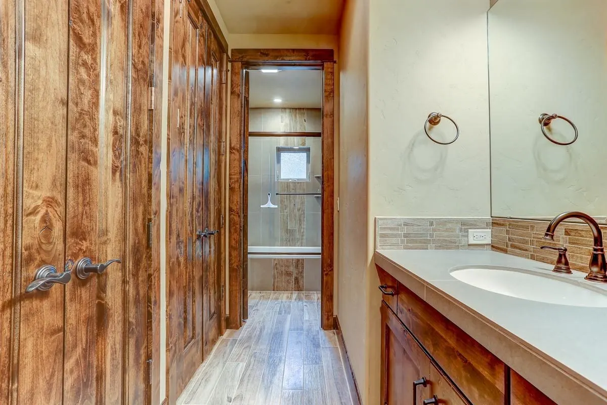 In front of the vanities is a linen closet with a stunning door with a wooden accent.