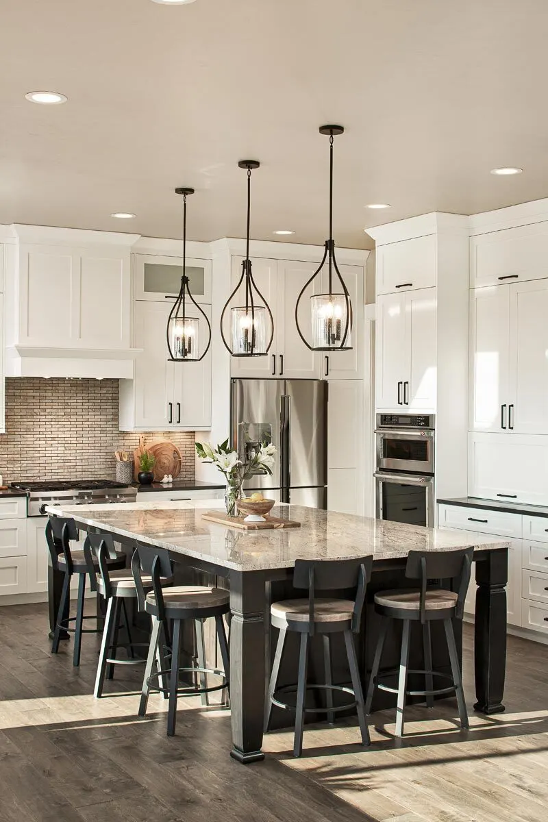 An interior white kitchen with a visible brick-style wall near the stove.