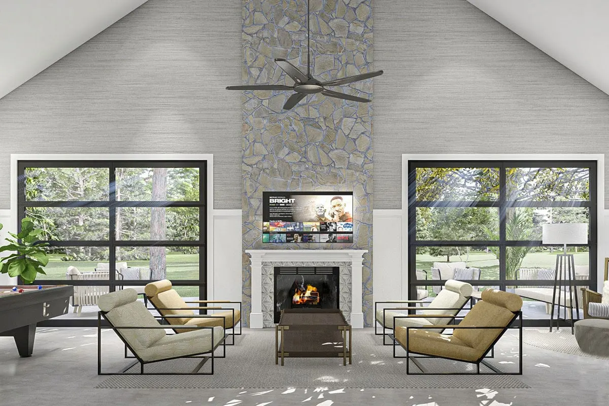 The lounge room or entertainment room that features a fireplace, a fan chandelier suspended from the ceiling, and two enormous glass windows.