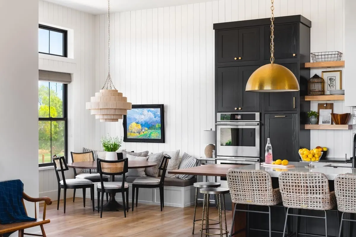The dining space, which features a distinctive chandelier design above, complements the black and white kitchen.
