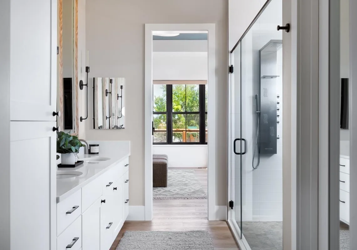 The immaculate view ambiance of the bathroom with glass design shower and white vanity is appealing.
