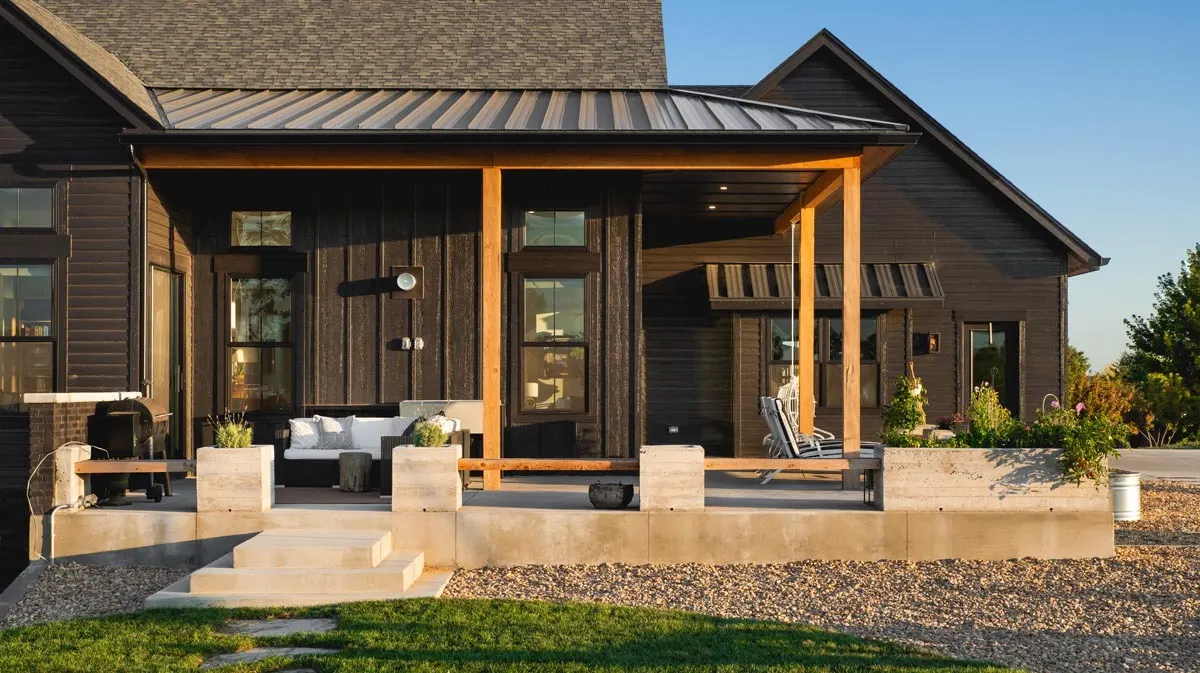 The covered patio on the left side of the home with stone steps complements the design