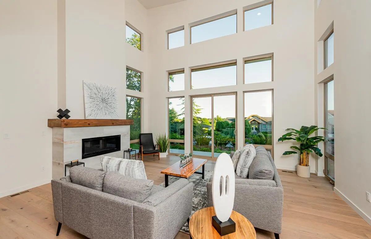Comfortable gray lounge chairs and glossy wood tables are in the living room area.