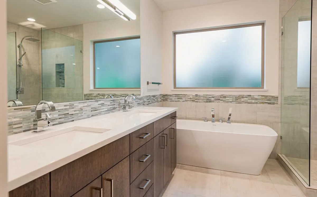 Vanities featuring clean white counters, huge mirrors, and wooden accent drawers.