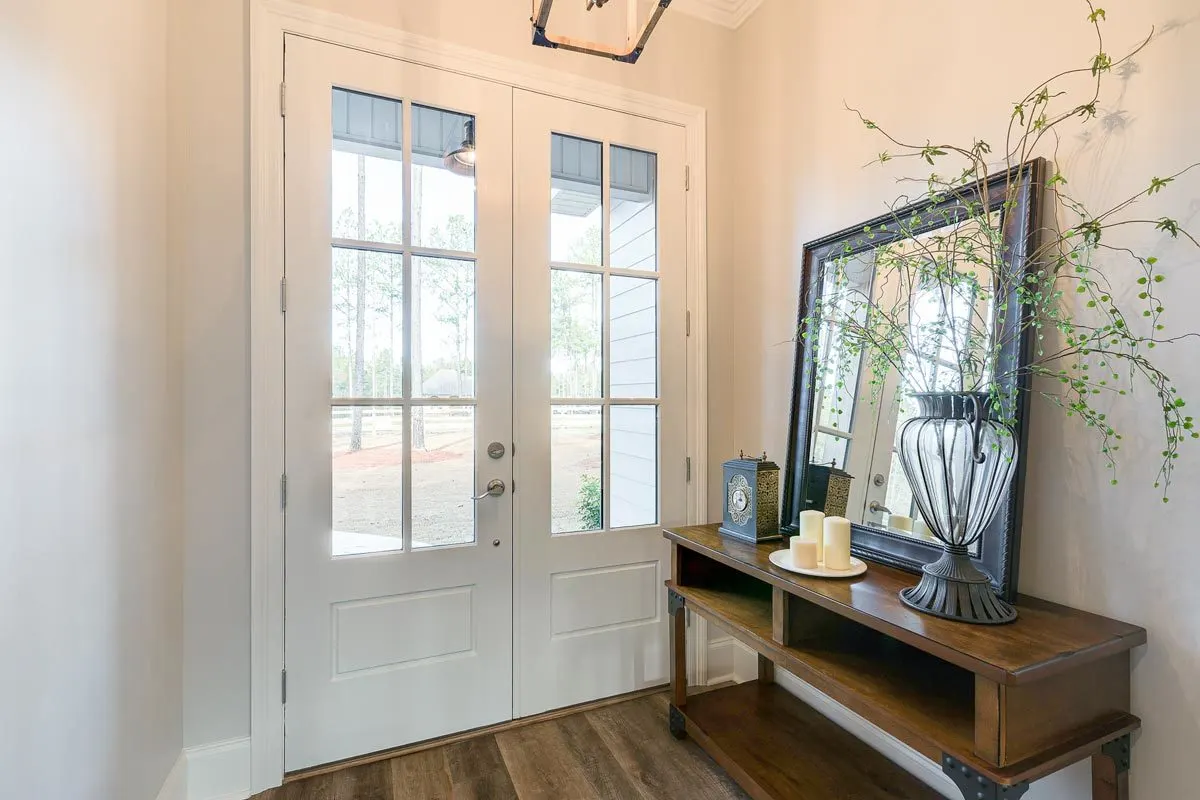 The farmhouse's entrance features a white French door and a glamour table in the doorway.