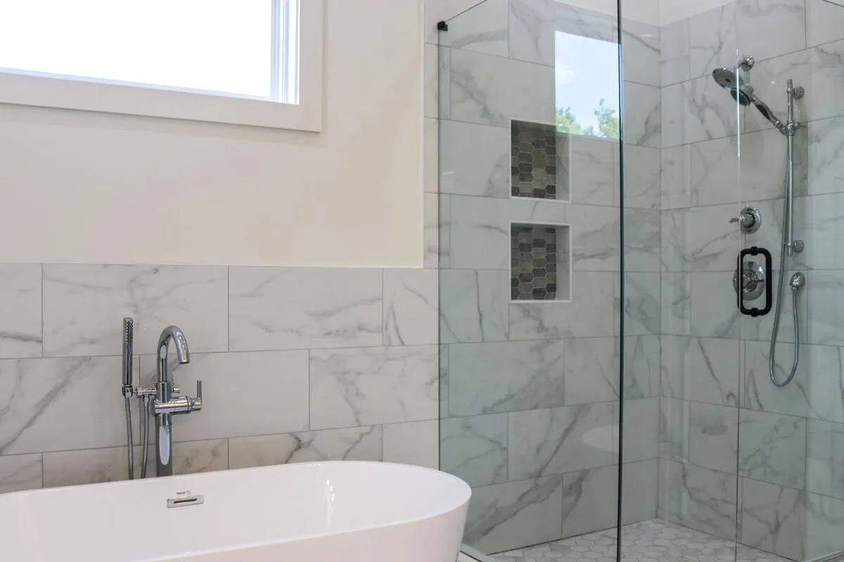 Glass-framed shower area close to the bathtub.