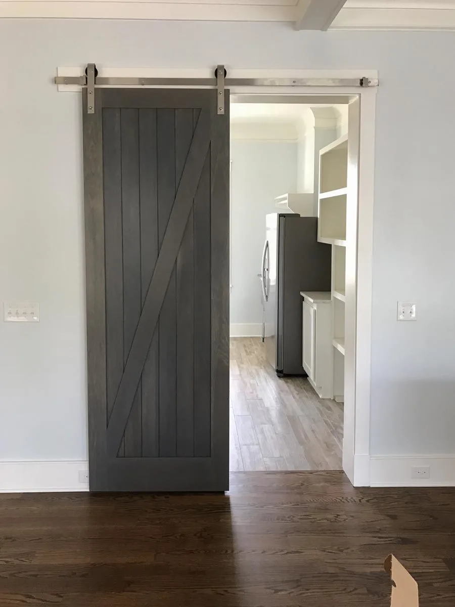 Barn style door for pantry with shelves and a refrigerator.
