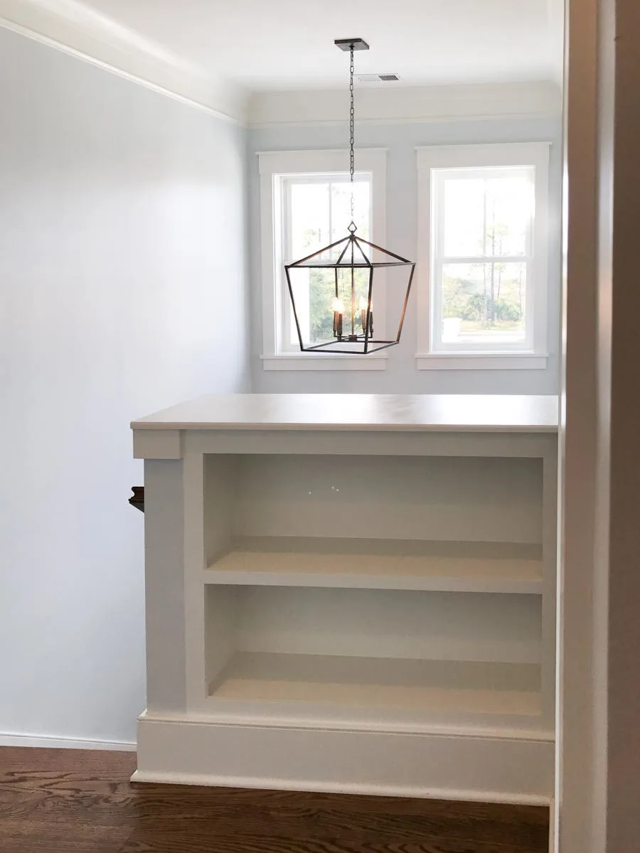 A white wood foundation bookcase near the stairs.