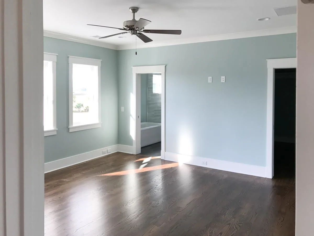The master bedroom has a chic blue wall color and a visible entrance to the bath.
