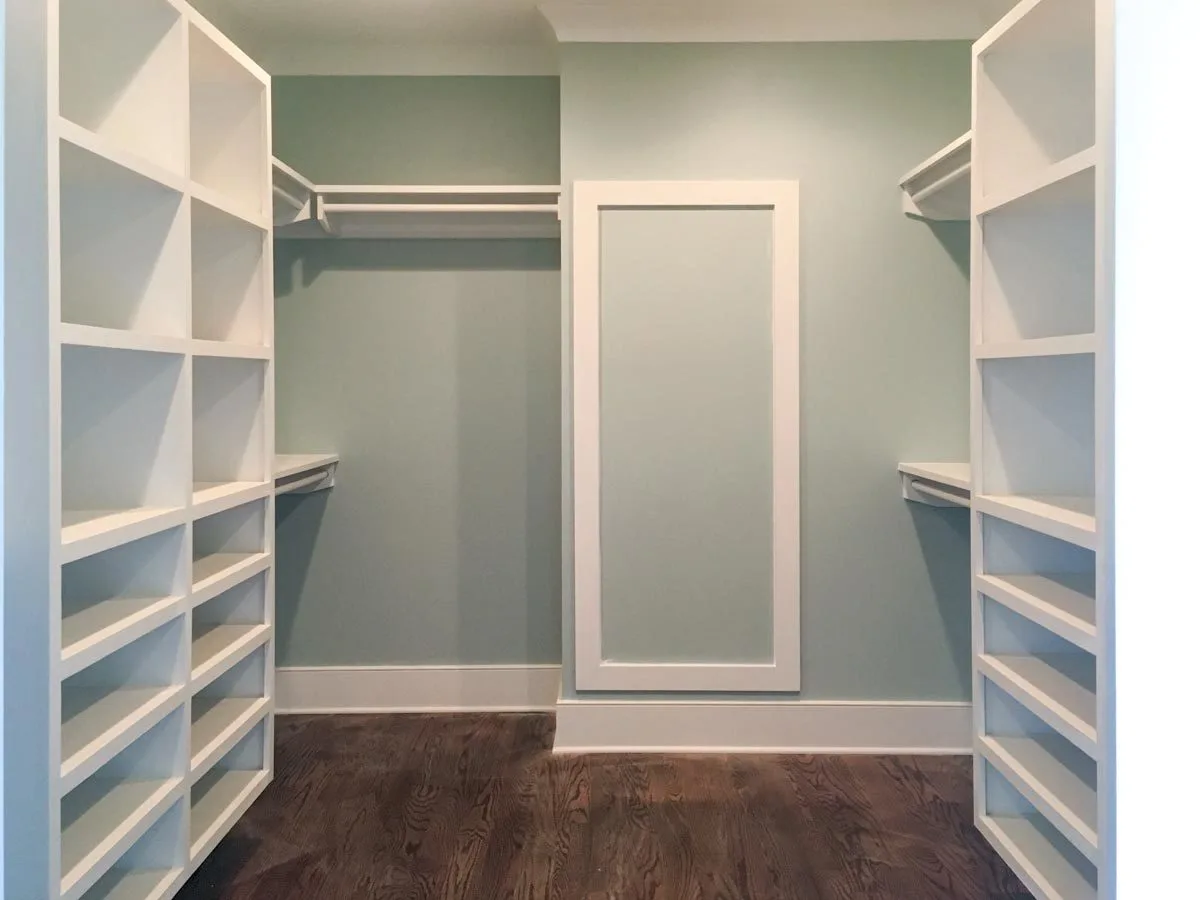 A walk-in closet with white-painted shelves and a rack.