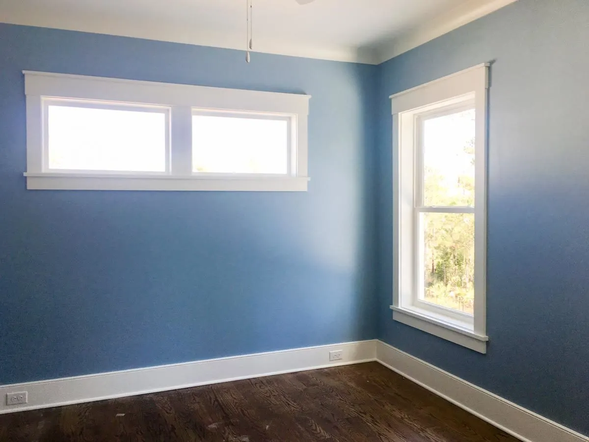 Another powder blue bedroom with a window in a white frame.
