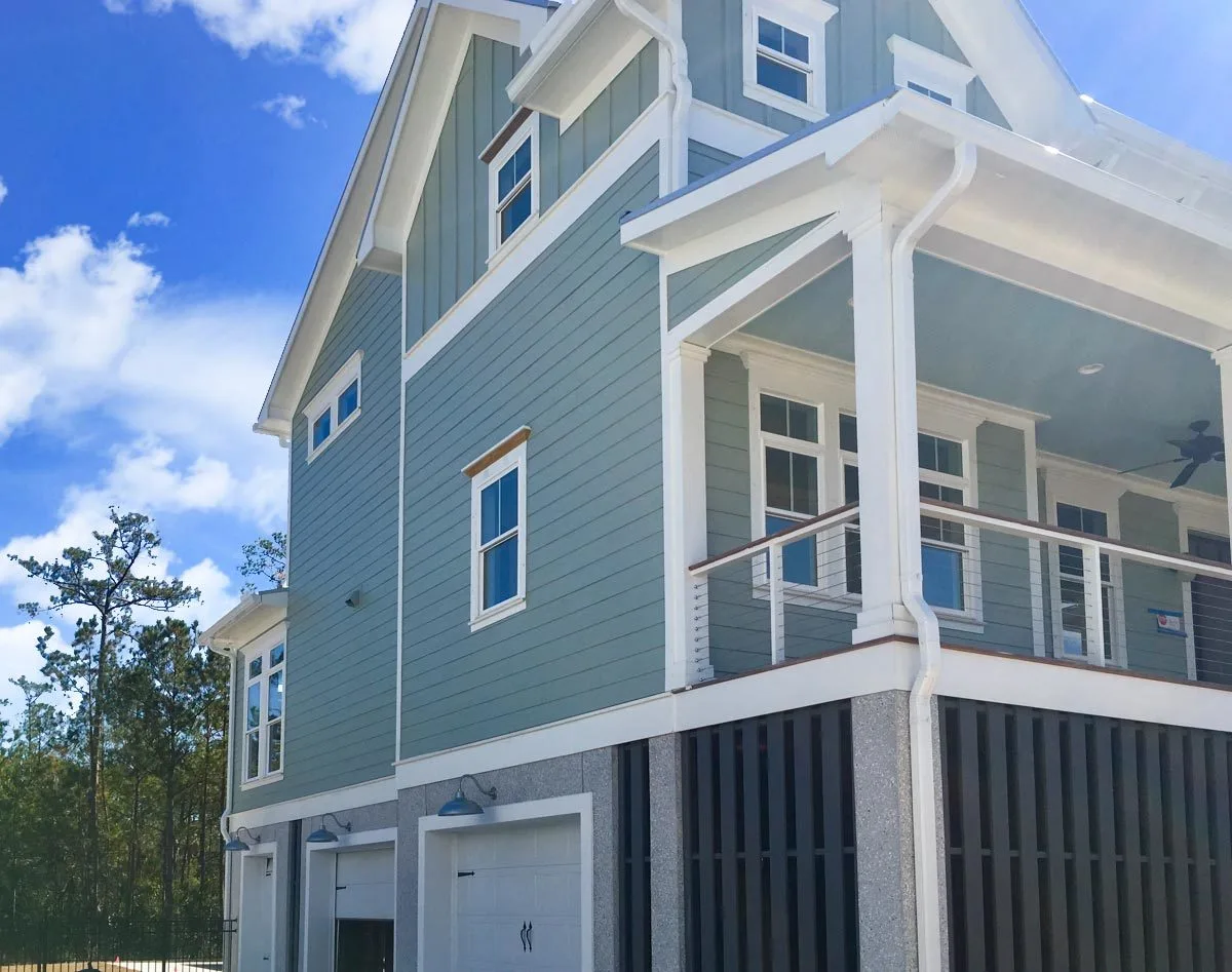 On the left side of the home, there is a garage with three white-painted doors.