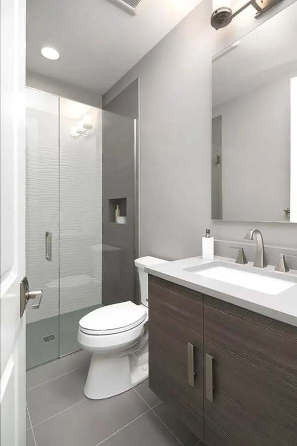 Small shower, toilet, and vanity in the bathroom.