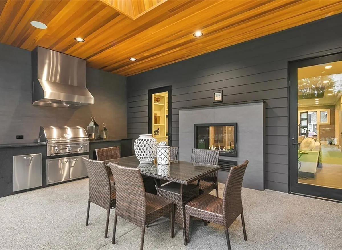 Outdoor kitchen with a grilling area and a brown table and chairs.