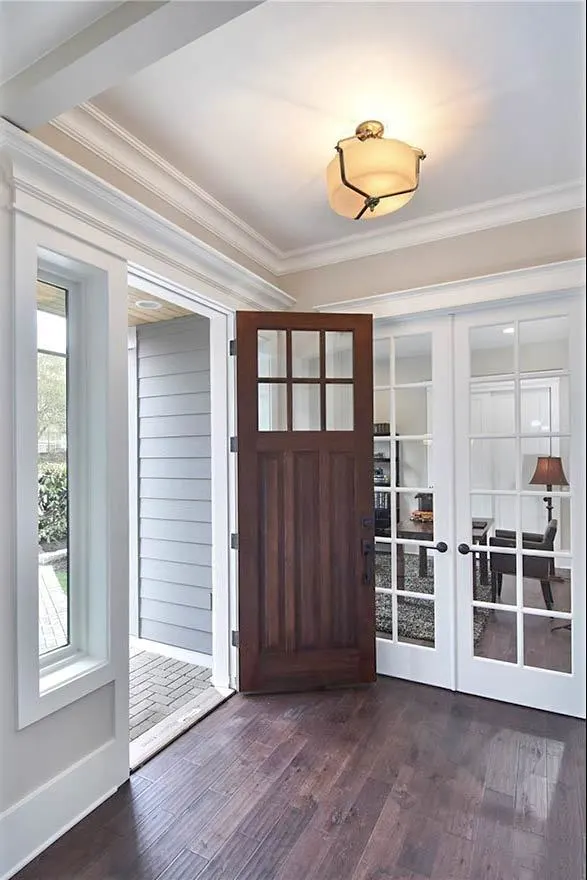 The main entry of the house with a wooden door and vinyl floor.