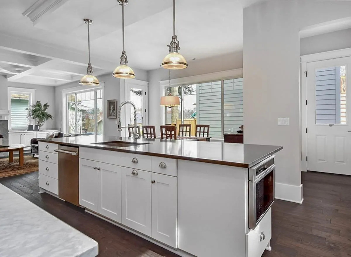 The white kitchen island with dishwasher, oven and lots of cabinet for space along with the marble countertop.
