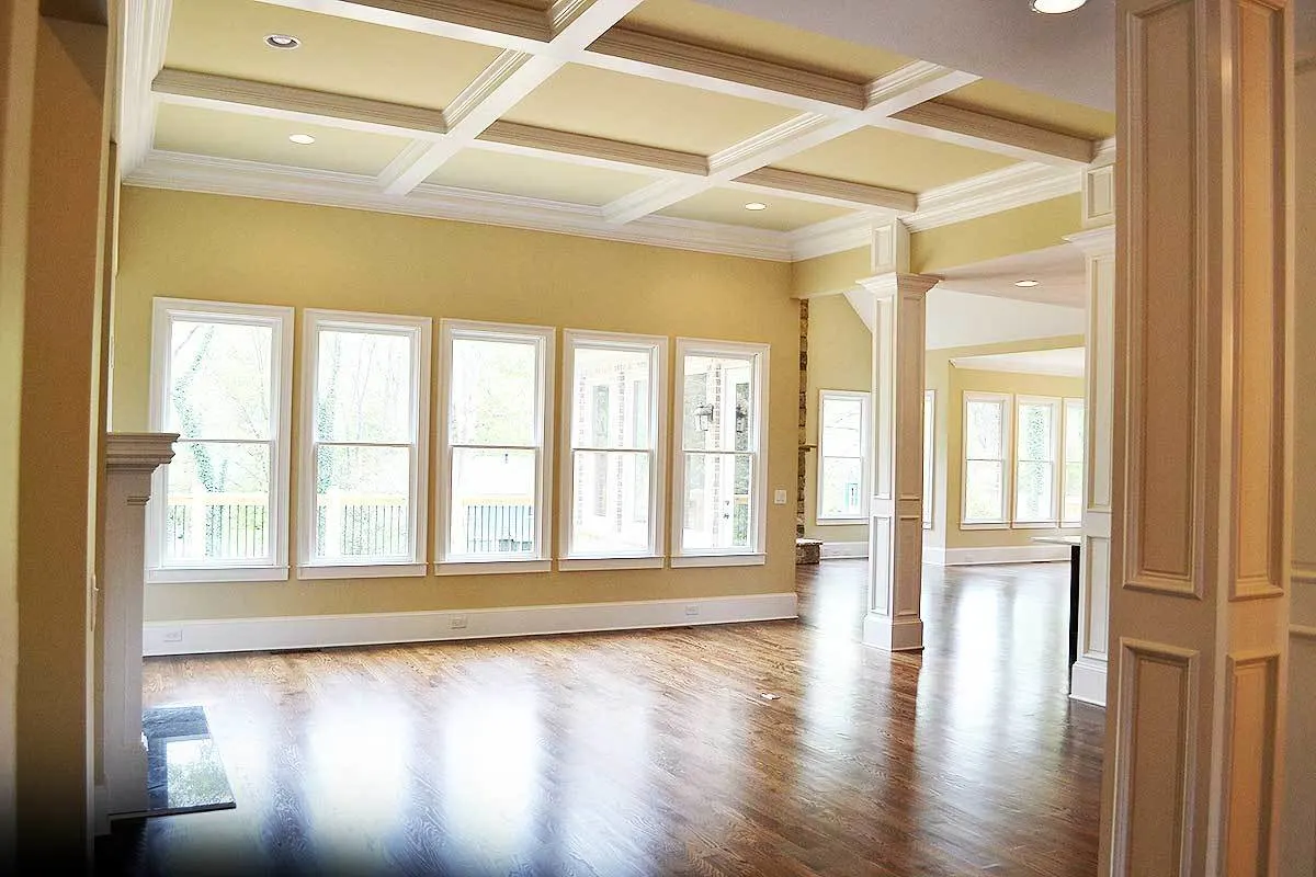 The great room has wide vertical windows and an interior of a cream hue.