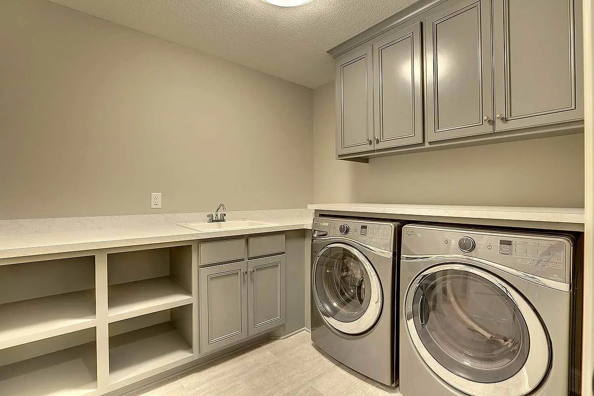 The handy laundry area with overhead cabinets and countertops for folding clothes and a sink.