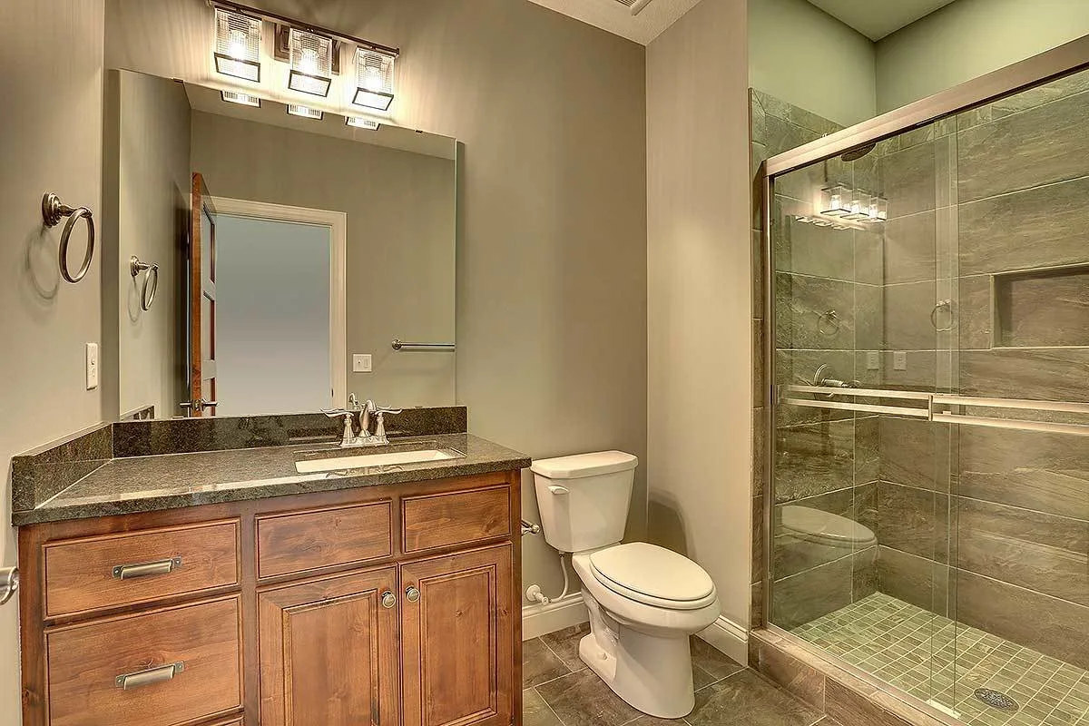 The bathroom area with glass shower area and wooden cabinet with marble sink.
