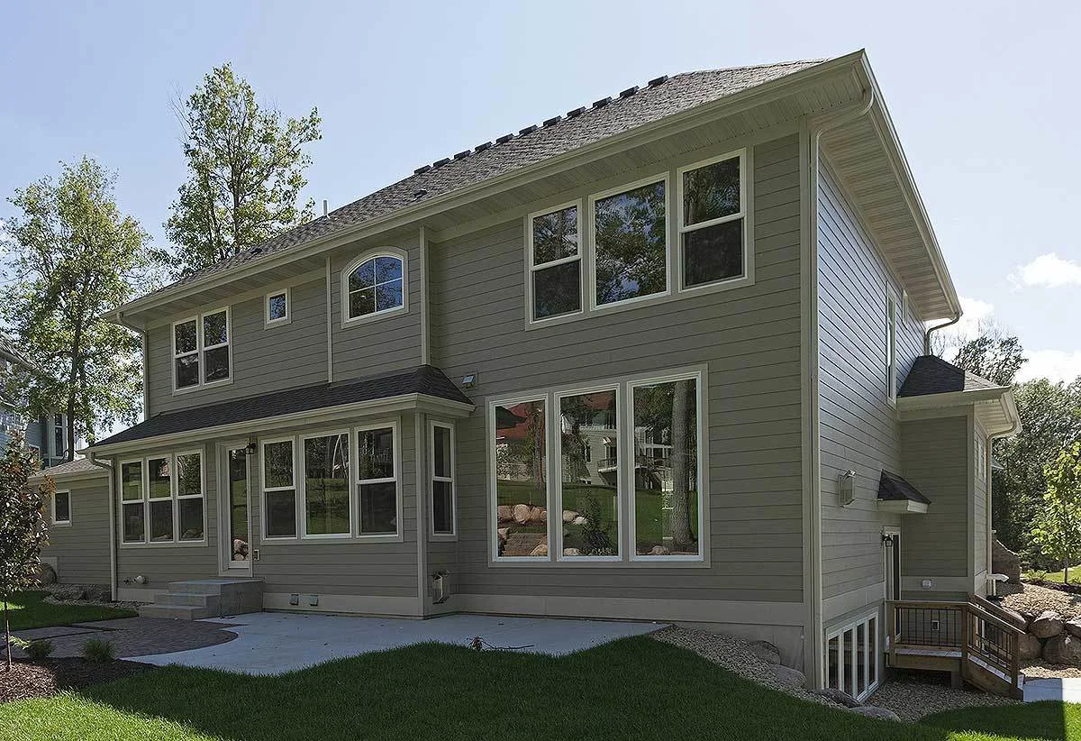 The back side view of the country farmhouse showcasing its exquisite design of glass windows.