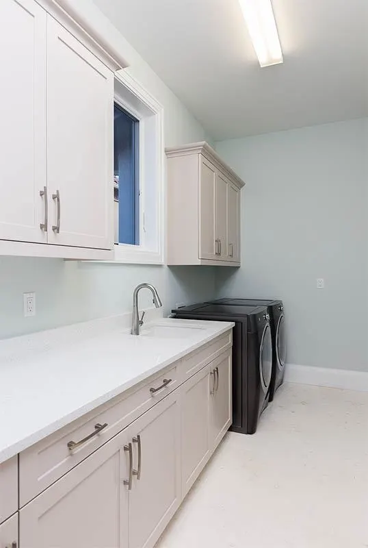 Laundry room with beige cabinetry as well as a dryer and a washer in black.
