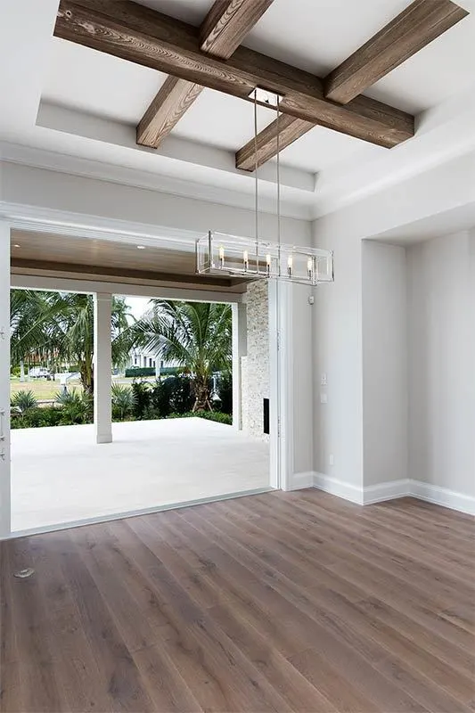 Dining area with exposed beam wood ceiling and linear candle chandelier.