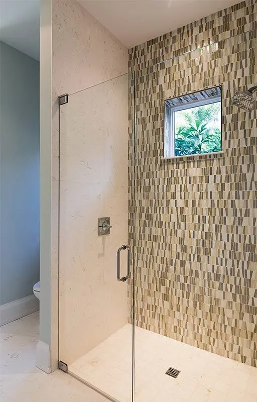 Another shower area with square tile flooring and a brown tone pattern tile wall.